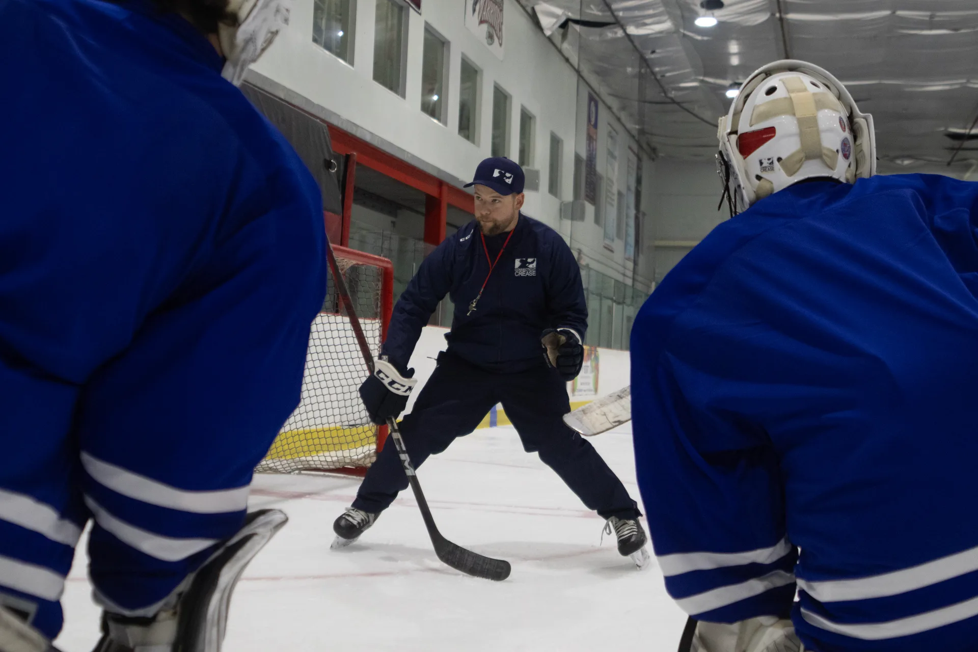 Coach demonstrating technique to a group of goalies