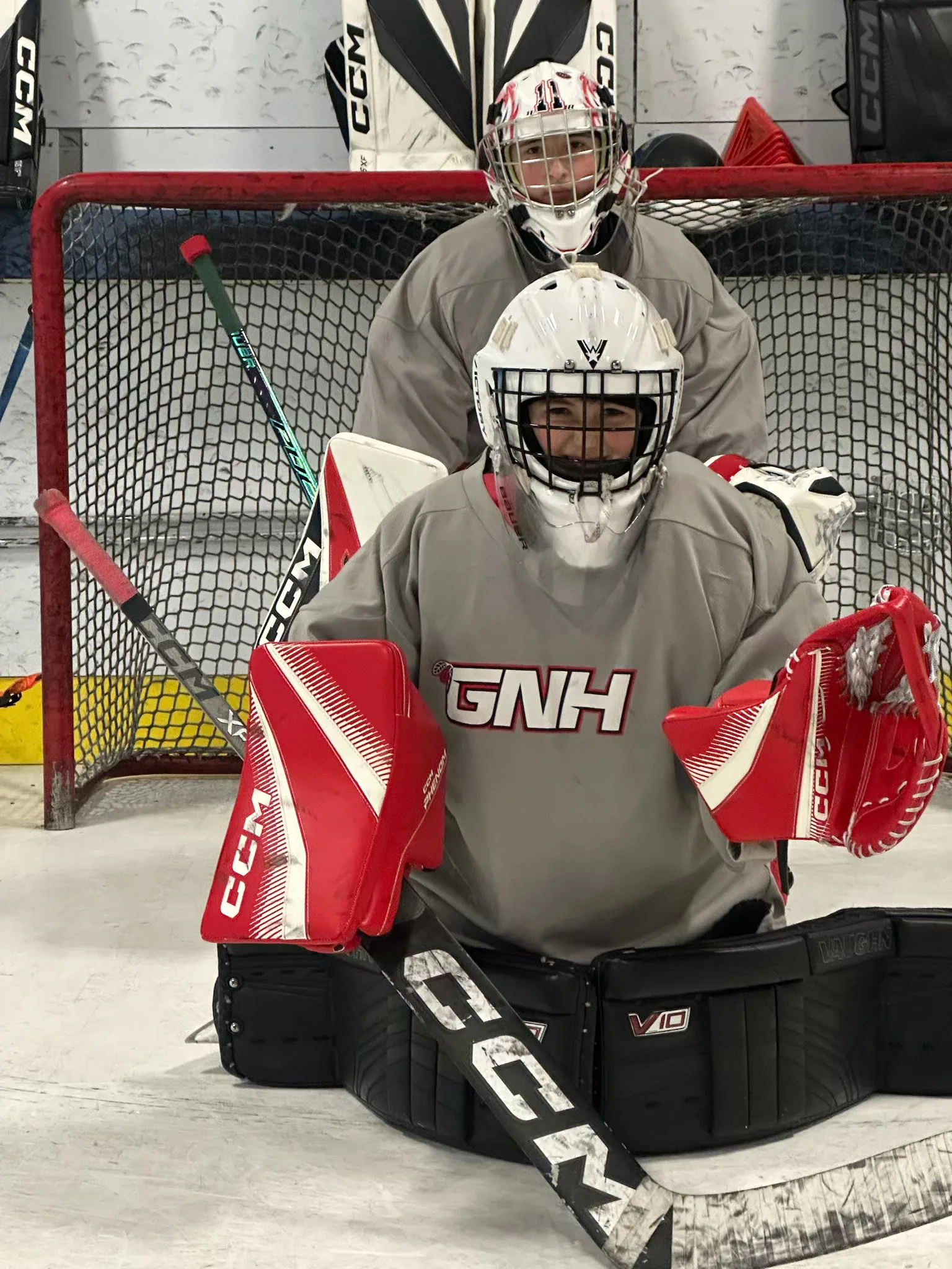 Coach working with two goalies in a 2-on-1 training session