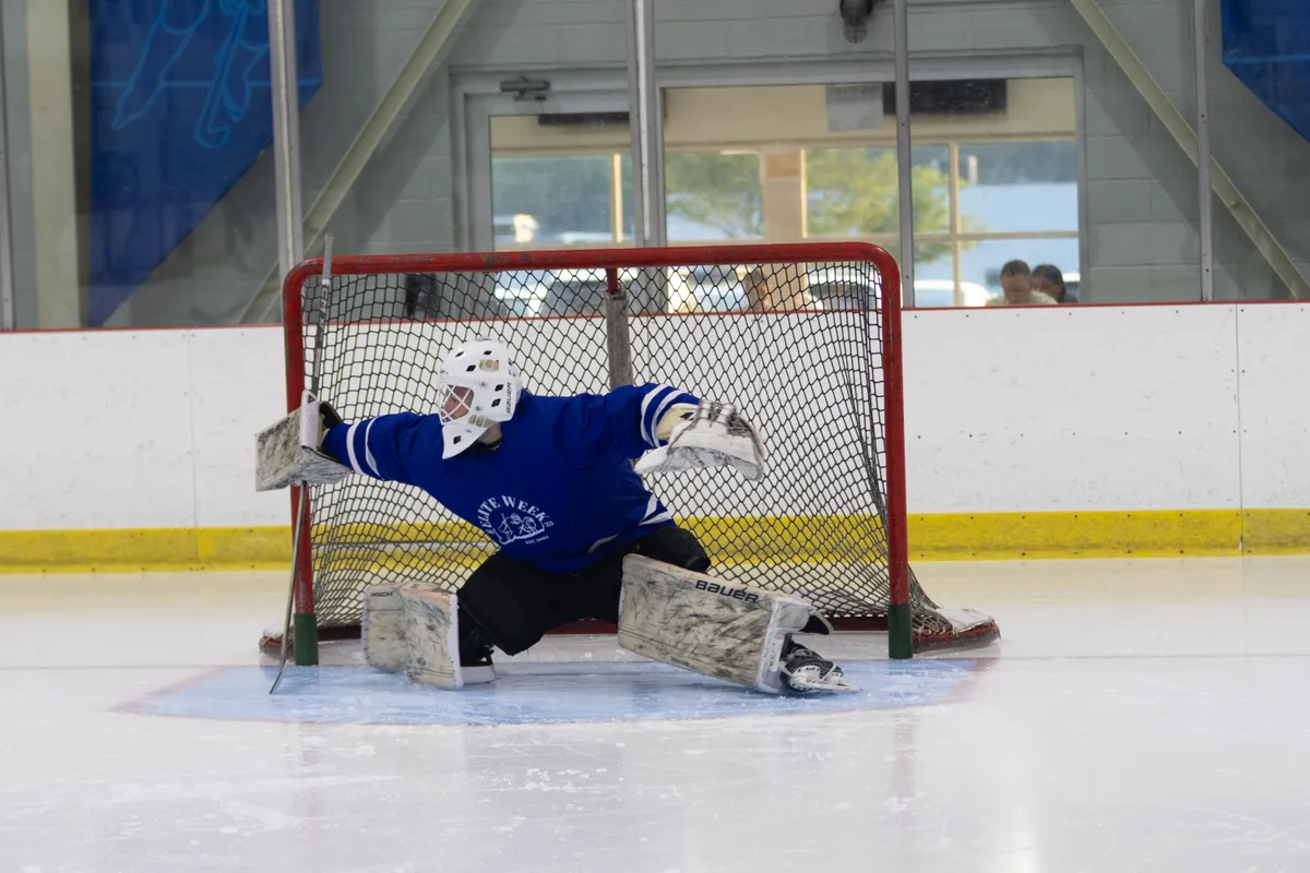 Goalie making a stretch save during an on-ice Breakfast Club lesson